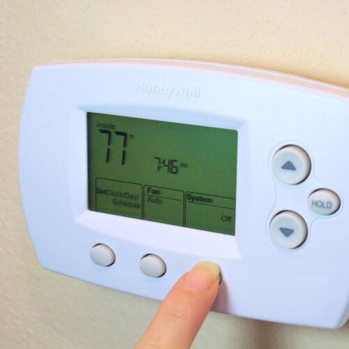 hand adjusting a thermostat