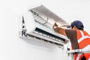 Man-Repairing-Ductless-Air-Conditioner A Man Repairing a Ductless Air Conditioner